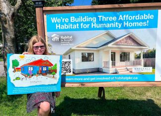 Eight-year-old Nora, who will be moving with her mother and grandmother into one of the three single-family homes in Norwood being constructed by Habitat for Humanity Peterborough & Kawartha Region (Habitat PKR), displays her artwork of the new home designed by Marshall Design Studios during a ground-breaking ceremony on July 14, 2026. (Photo: Habitat PKR)