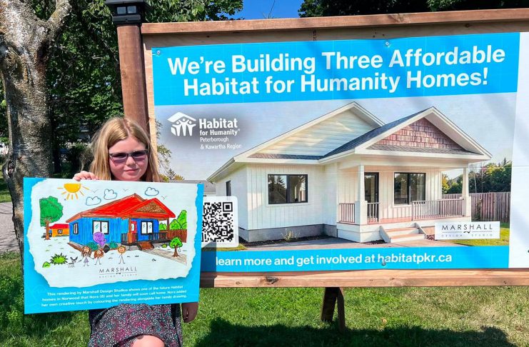 Eight-year-old Nora, who will be moving with her mother and grandmother into one of the three single-family homes in Norwood being constructed by Habitat for Humanity Peterborough & Kawartha Region (Habitat PKR), displays her artwork of the new home designed by Marshall Design Studios during a ground-breaking ceremony on July 14, 2026. (Photo: Habitat PKR)