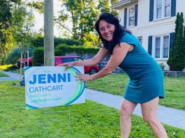 Jenni Cathcart, one of four candidates vying for two Town Ward seats on Peterborough city council in the October municipal election, placing an election lawn sign. The first-time candidate tells kawarthaNOW that three of her election signs, including one on the lawn of her own Homewood Avenue home, were taken by someone in the middle of the day on July 20, 2026. (Photo courtesy of Jenni Cathcart campaign)