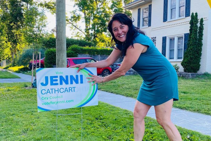 Jenni Cathcart, one of four candidates vying for two Town Ward seats on Peterborough city council in the October municipal election, placing an election lawn sign. The first-time candidate tells kawarthaNOW that three of her election signs, including one on the lawn of her own Homewood Avenue home, were taken by someone in the middle of the day on July 20, 2026. (Photo courtesy of Jenni Cathcart campaign)