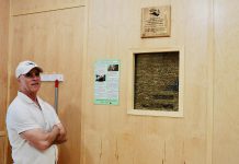 Camp Kawartha's executive director Jacob Rodenburg inside the newest addition to the camp, Birch Cabin, next to a "truth window." These small portals into the walls show the straw bale insulation holding up many of the camp's buildings and invite visitors to think about construction and consider sustainability in entirely new ways. (Photo: Rebekkah Hyams / GreenUP)
