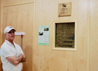 Camp Kawartha's executive director Jacob Rodenburg inside the newest addition to the camp, Birch Cabin, next to a "truth window." These small portals into the walls show the straw bale insulation holding up many of the camp's buildings and invite visitors to think about construction and consider sustainability in entirely new ways. (Photo: Rebekkah Hyams / GreenUP)