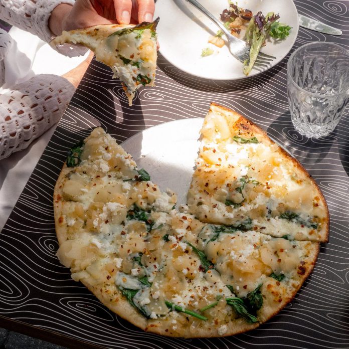 Since 1999, Night Kitchen Pizzeria has been slinging homemade pizza in downtown Peterborough. With the slogan "pizza that never played by the rules," the restaurant is known for curating pizzas with innovative toppings like strawberries, blueberries, and unique cheeses. Pictured is the customer favourite Bugle, made with the signature pesto, spinach, caramelized onions, pear, goat feta, and chili flakes. (Photo courtesy of Night Kitchen Pizzeria)
