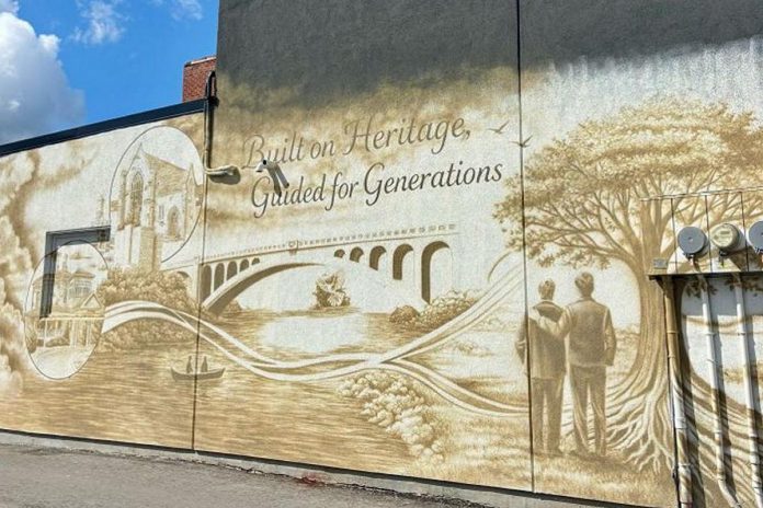 Peterborough artist John Leacy's new mural at Heritage Wealth Services at 61 Hunter Street East in Peterborough's East City reflects the firm's "Built on Heritage, Guided for Generations" philosophy through images of local landmarks, family, and growth. (Photo: Ashburnham Realty)