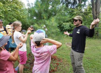 Nature, play, and community connection celebrated during GreenUP Ecology Park’s Family Night GreenUP Ecology Park program coordinator Jonathan Armstrong showed participants how to determine the age of a pine tree during a tree tour he led on Family Night at the park on Peterborough on August 27, 2026. (Photo: Alex Karn / GreenUP)