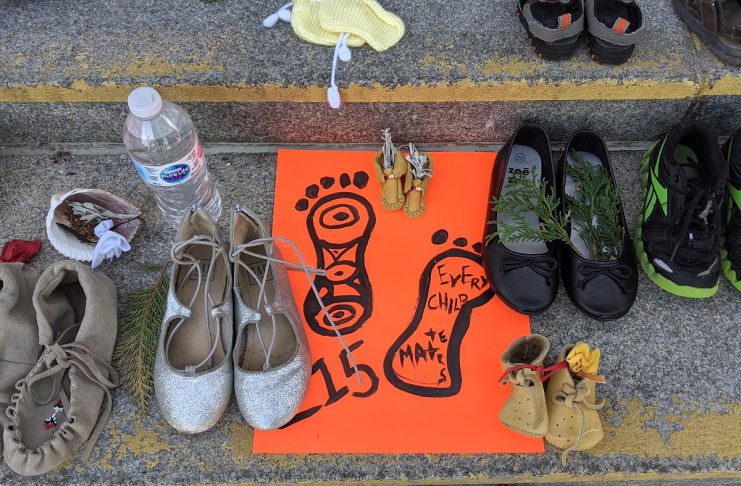 Children's shoes, toys, and offerings on the steps of Peterborough City Hall in June 2021 as part of a community memorial created in response to the discovery of the remains of 215 Indigenous children buried at the former Kamloops Indian Residential School in British Columbia. As well as remembering and honouring those lost to residential schools and the thousands of survivors, National Day for Truth and Reconciliation is a day for Canadians to educate themselves about the heritage, culture, stories, and experiences of First Nations, Inuit, and Métis peoples. (Photo: Bruce Head / kawarthaNOW)
