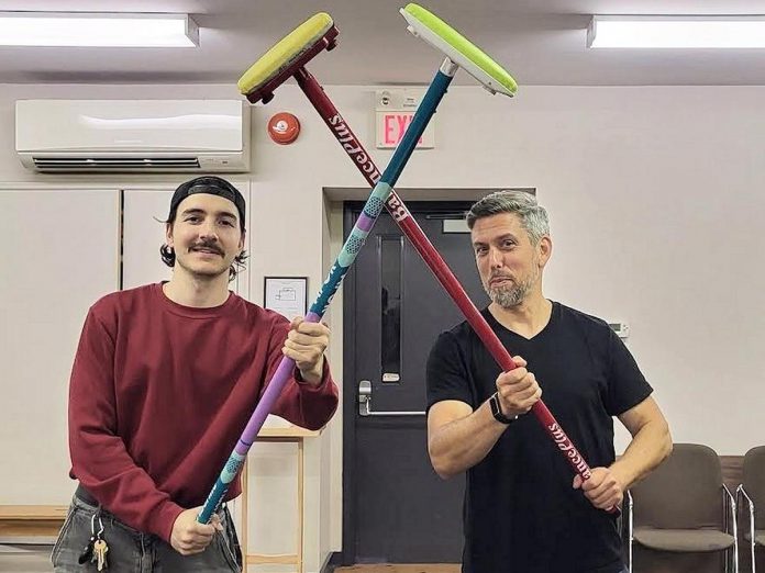 Hank Murray as Bill and Jeremy Brans as Johnny during a rehearsal for the Northumberland Players production of Kristen Da Silva's curling comedy "Hurry Hard" at the Best Western in Cobourg from October 23 to November 8, 2026. (Photo: Northumberland Players / Facebook)
