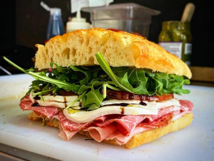 One of the most popular sandwiches you'll find at Muster Point in Bobcaygeon is the Meat Trio, made with salami, capicollo ham, and mortadella alongside fresh mozzarella cheese, fior di latte cheese, pesto, and balsamic glaze. All of this is served on a housemade focaccia bun. (Photo courtesy of Muster Point)