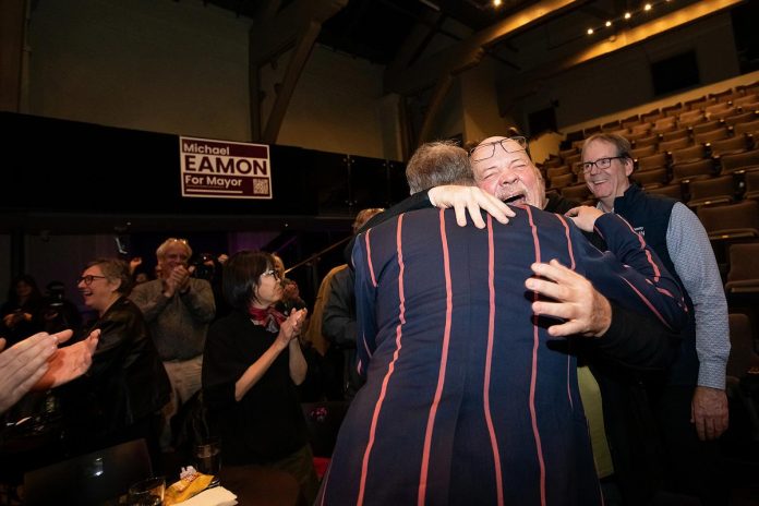 A jubilant Jim Russell, the retired CEO of United Way Peterborough & District, hugs mayor-elect Michael Eamon at Market Hall Performing Arts Centre in downtown Peterborough on October 26, 2026. (Photo: Jordan Lyall / kawarthaNOW)