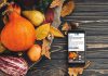 A smartphone sitting on a harvest table covered with squash and fall leaves displaying kawarthaNOW's Thanksgiving Monday 2026 holiday hours story. (kawarthaNOW photo)