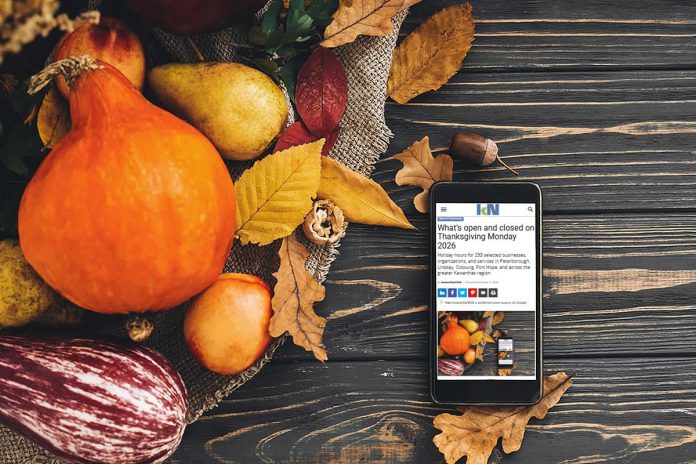 A smartphone sitting on a harvest table covered with squash and fall leaves displaying kawarthaNOW's Thanksgiving Monday 2026 holiday hours story. (kawarthaNOW photo)