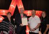 Peterborough mayor Jeff Leal presents a certificate of recognition of five years of family ownership from the City of Peterborough to The Venue owners April Sendel (left) and Kevin Sendel (second from right) and general manager Tiffany Daskewich (right) during a celebration at the downtown Peterborough event space on October 13, 2026. (Photo: Joshua Gillis)