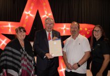 Peterborough mayor Jeff Leal presents a certificate of recognition of five years of family ownership from the City of Peterborough to The Venue owners April Sendel (left) and Kevin Sendel (second from right) and general manager Tiffany Daskewich (right) during a celebration at the downtown Peterborough event space on October 13, 2026. (Photo: Joshua Gillis)